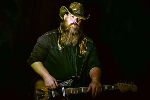 Outlaw State of Mind lead vocalist in a straw cowboy hat and dark shirt holding a Squier Jaguar guitar, performing a Chris Stapleton tribute.
